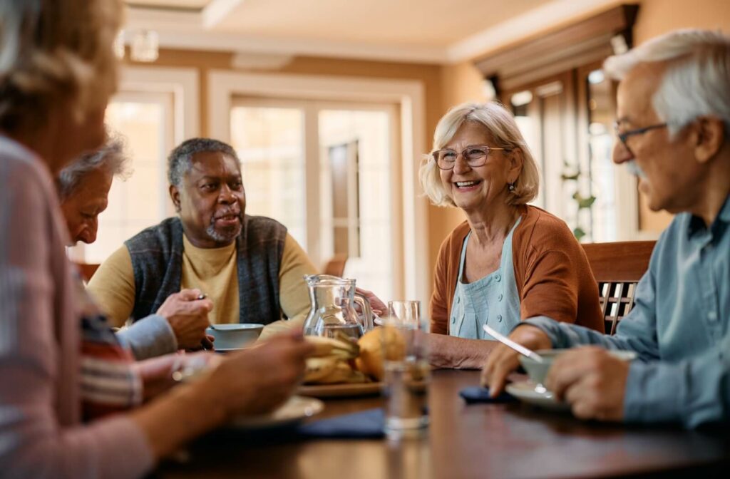 A group of seniors happily share a meal together in their senior living home.