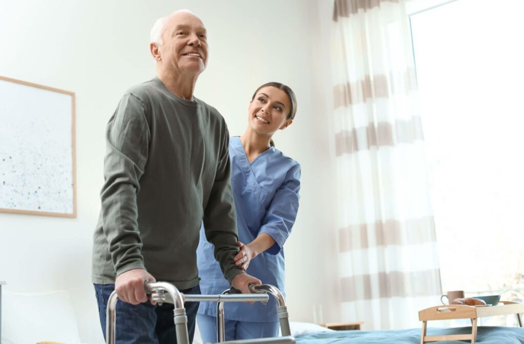 A nurse helps an older man practice walking with a walking aid while recovering from a hip injury in respite care