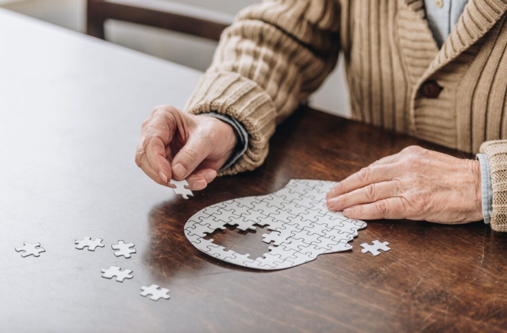 A senior fills out a puzzle of a human head, with pieces missing in the brain area, symbolizing memory loss from dementia
