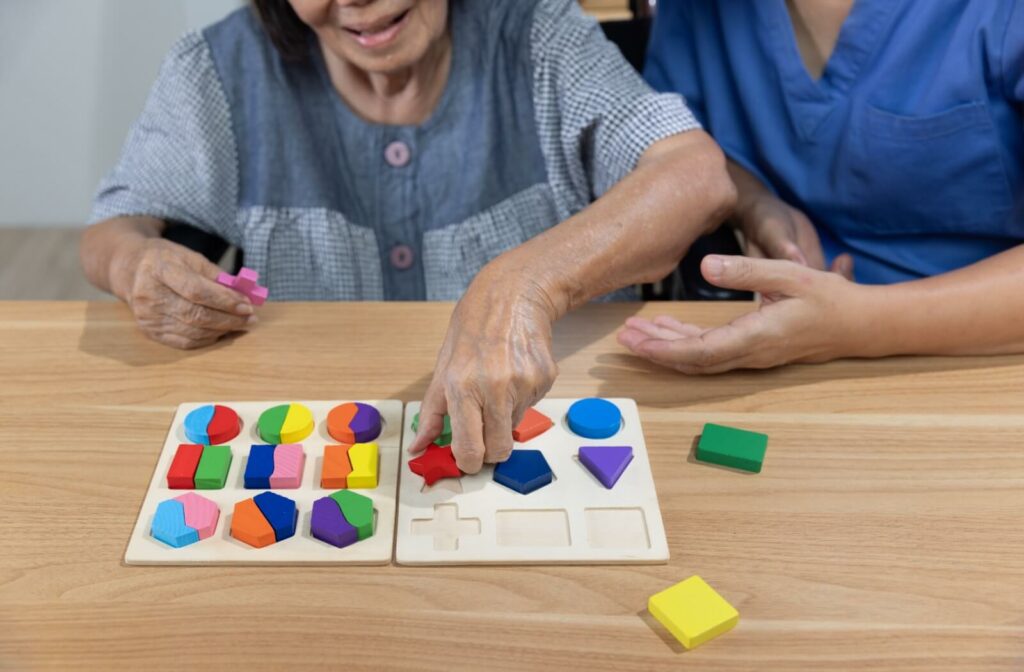 A nurse supports a senior with dementia in memory care with a colorful puzzle meant to support cognitive health
