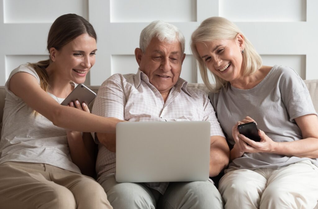 An adult child sitting with their older parents, getting excited while researching assisted living communities.