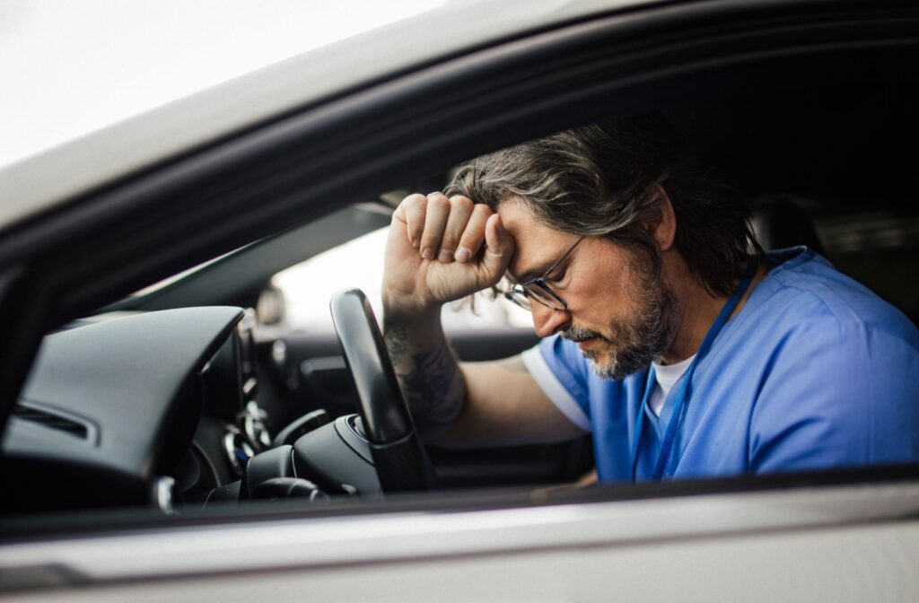 A caregiver in a car is feeling exhausted and sad.