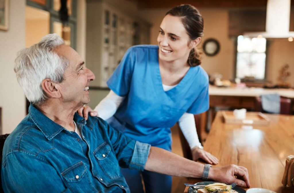 A senior adult smiles at a caregiver after having been served a meal