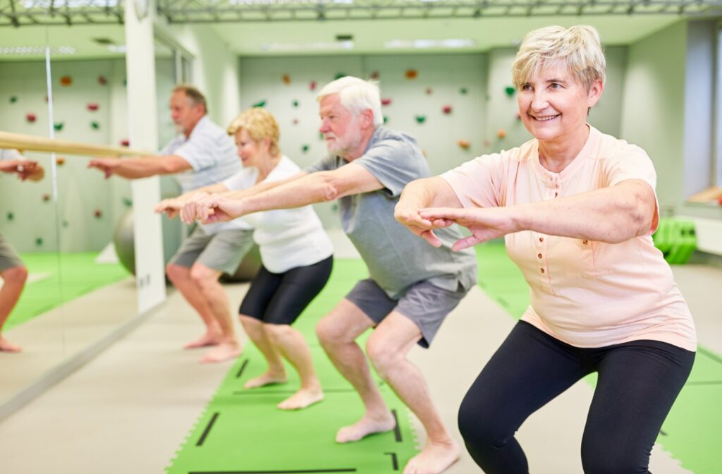 A group of seniors bend their knees in an exercise class.